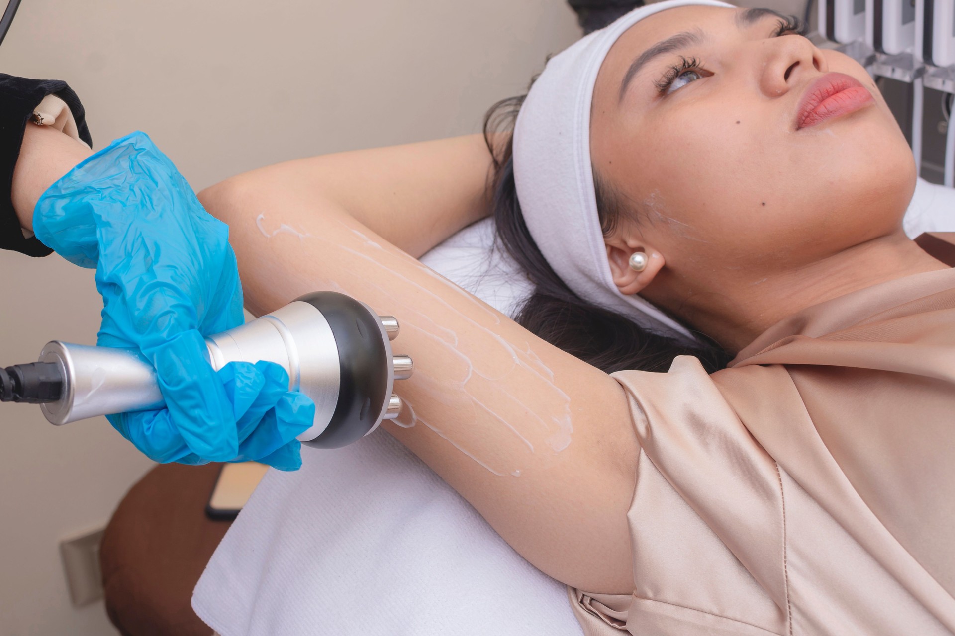 A young woman receives a radiofrequency upper arm skin tightening or slimming treatment. At a facial care, dermatologist or aesthetic clinic.